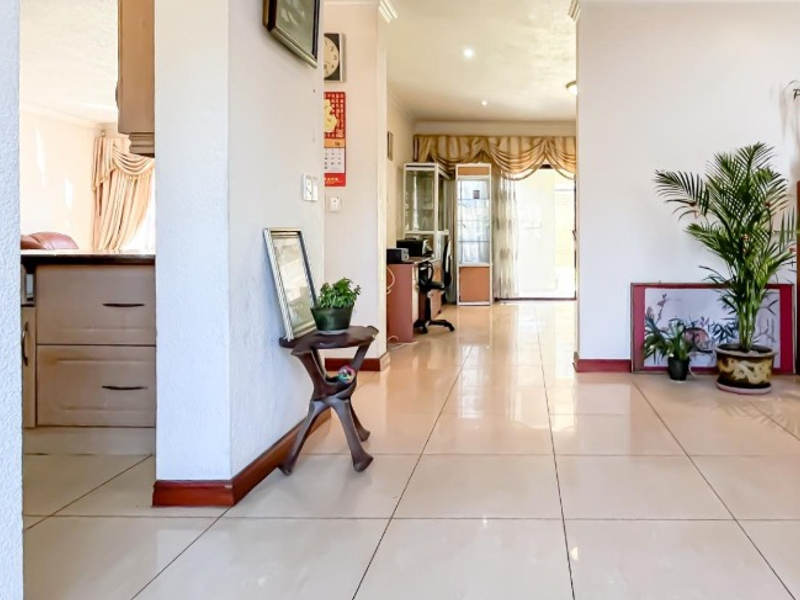 A bright, tiled hallway providing a central transition space between the living areas, featuring neutral walls and recessed lighting.