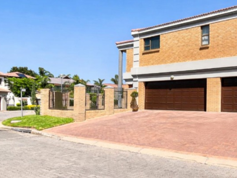 Front view of a double-story residential property featuring a paved driveway, double garage, and brick exterior finish.