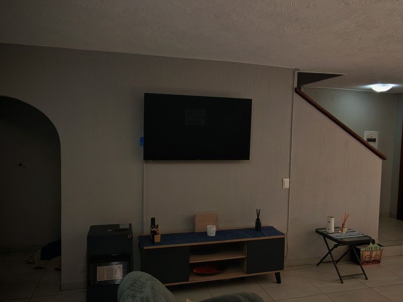 A living room area featuring an arched doorway, staircase, and tiled flooring, providing a functional layout for the home.