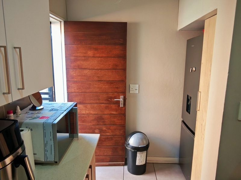 A functional kitchen area featuring built-in cabinetry, tiled flooring, and a direct access door leading to the exterior.