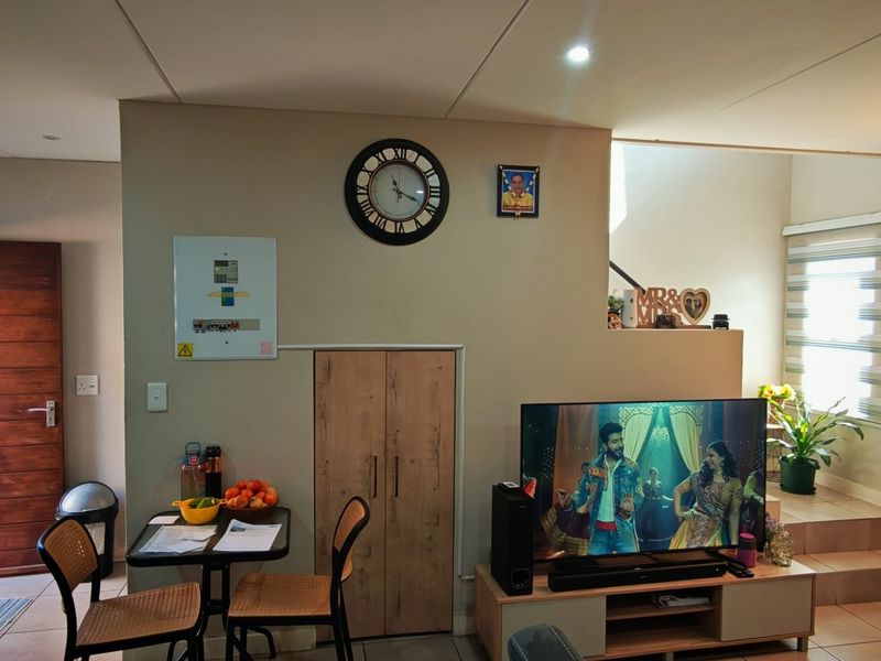 An open-plan living and kitchen area featuring tiled floors, built-in cabinetry, and modern lighting, providing a functional and connected living space.