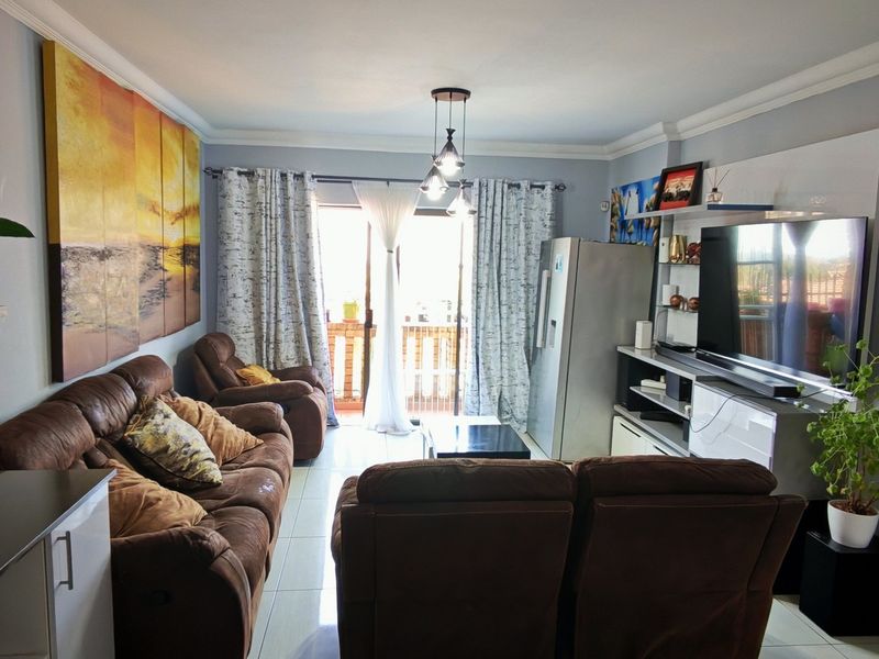 A comfortable living room featuring tiled flooring, crown molding, and a sliding glass door that provides access to an outdoor area.