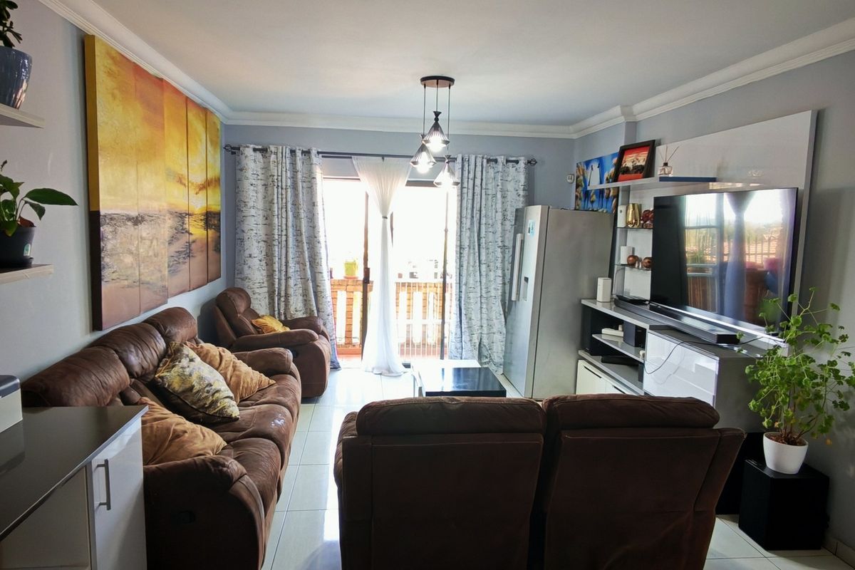 A comfortable living room featuring tiled flooring, crown molding, and a sliding glass door that provides access to an outdoor area.