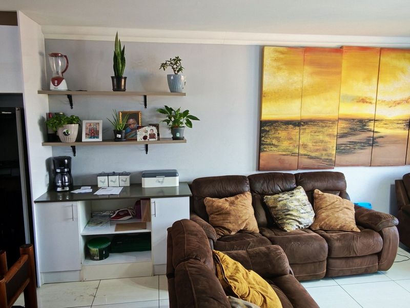 Open-plan living area featuring tiled flooring, built-in cabinetry with floating shelves, and coved ceiling cornices, creating a functional and connected living space.