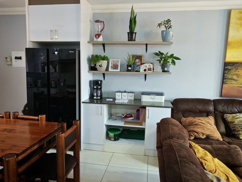 Open plan living and dining area featuring tiled flooring, built-in cabinetry, and floating shelving units.