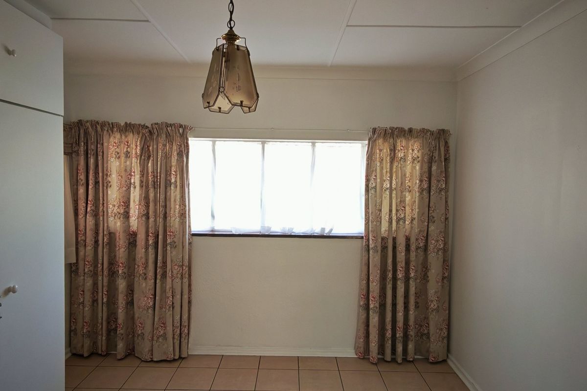 A vacant bedroom featuring tiled flooring, a built-in wardrobe, and a central pendant light fixture.