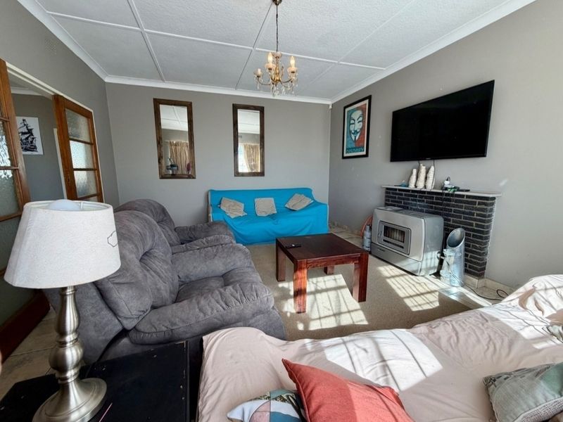 A living room featuring a brick fireplace, tiled ceiling, and carpet flooring, offering a functional space with potential for cosmetic updates.
