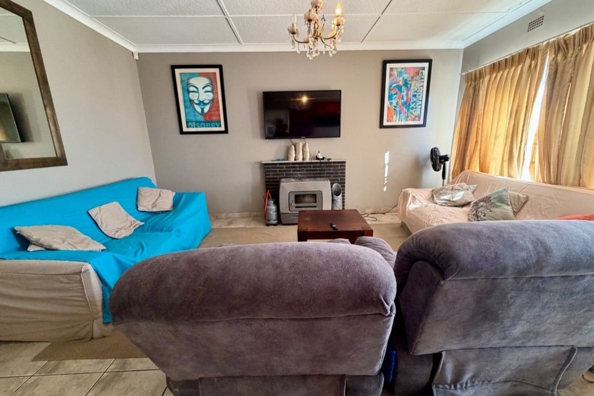 A living room featuring a brick fireplace, tiled flooring, and ceiling tiles, offering a functional space with potential for modernization.