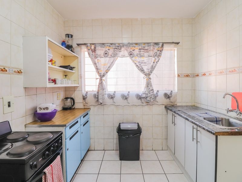 A functional kitchen featuring tiled walls and floors, built-in cabinetry, and a stainless steel sink, offering potential for a modern renovation.