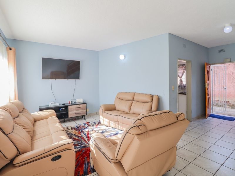 A functional living room featuring tiled flooring, light blue walls, and direct access to an exterior area through a security gate.