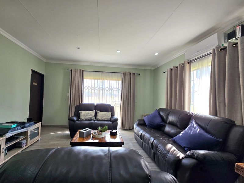 A well-maintained living room featuring tiled flooring, recessed lighting, and a wall-mounted air conditioning unit, providing a comfortable and functional space.
