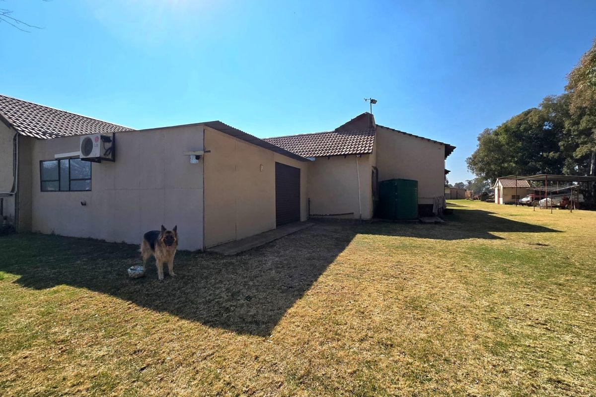 Rear view of the property showing the exterior wall, tiled roof, water storage tank, and an installed air conditioning unit.