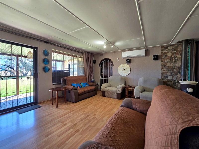 Living room featuring laminate flooring, a stone accent wall with a wood-burning stove, and direct access to the outdoor patio area.