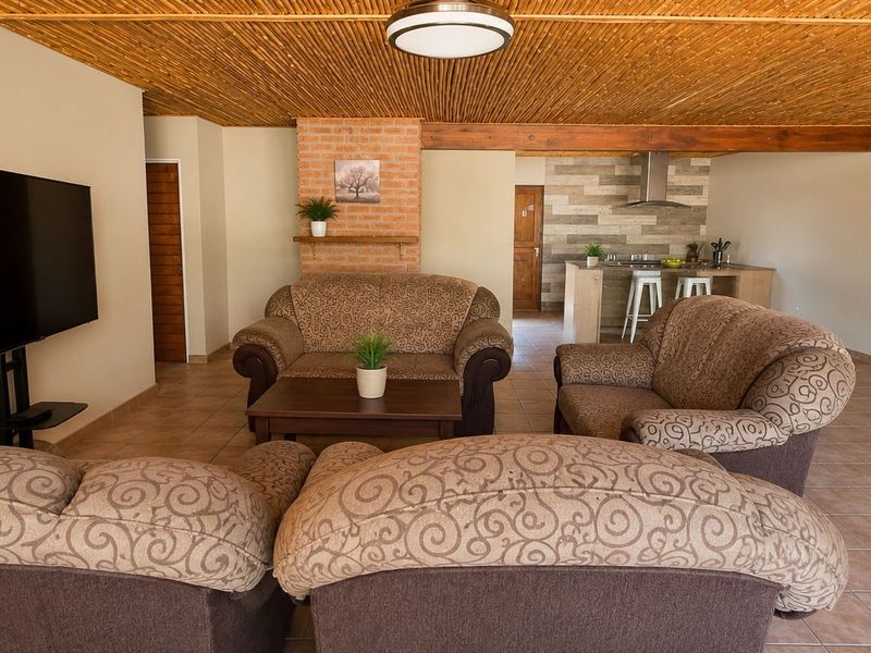 Open plan living area featuring a rustic reed ceiling, brick fireplace, and a functional kitchen island with integrated extractor fan.