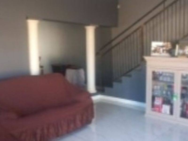 Living area featuring a staircase with a metal balustrade, decorative columns, and tiled flooring.