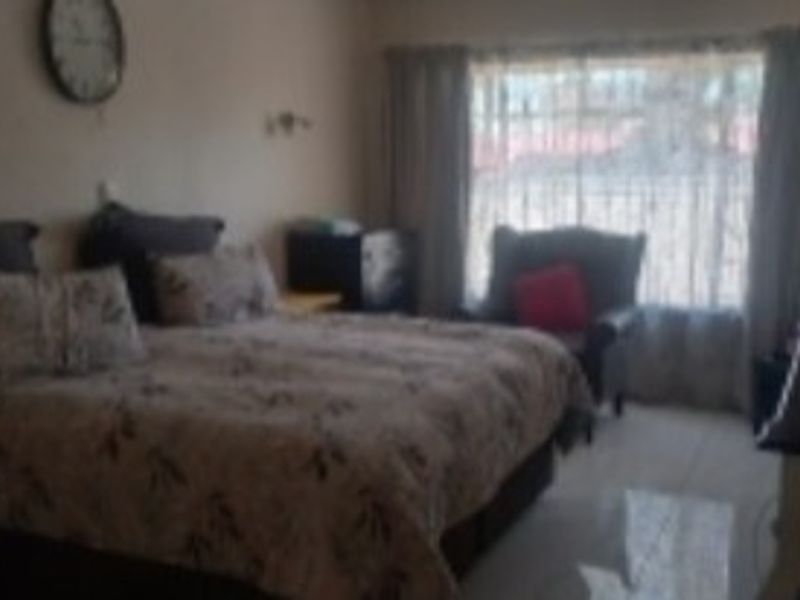 A bedroom featuring tiled flooring and window treatments, offering a functional space for rest.