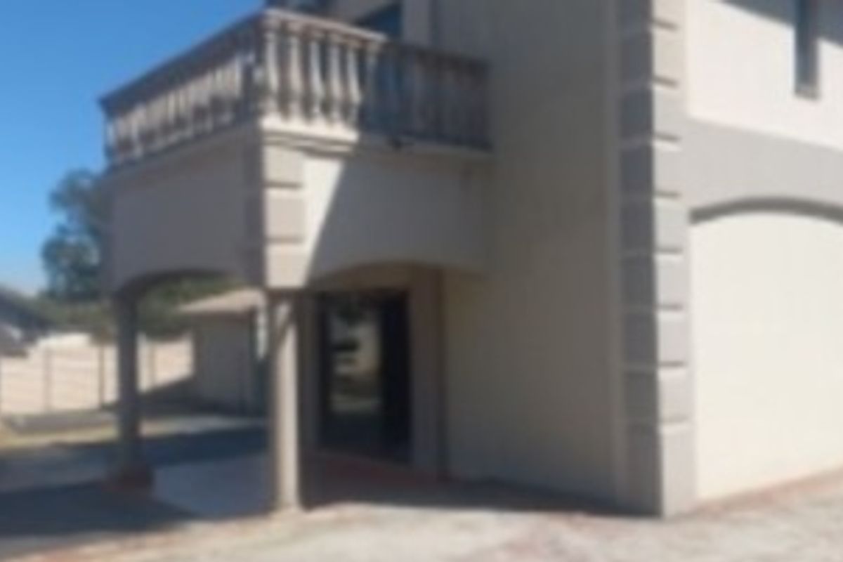 Rear view of the property featuring a covered patio area and an upper-level balcony with a balustrade.