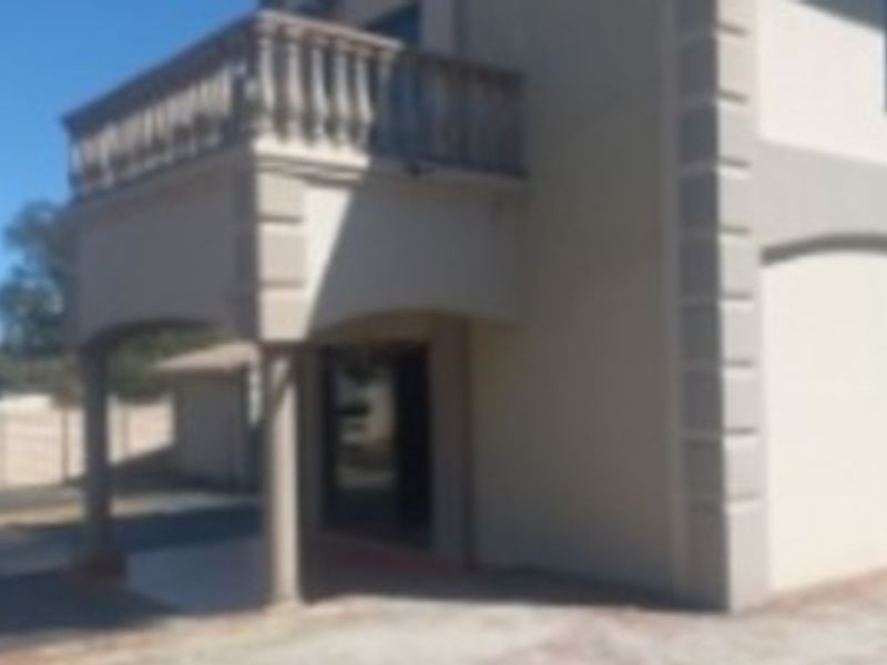 Rear view of the property featuring a covered patio area and an upper-level balcony with a balustrade.