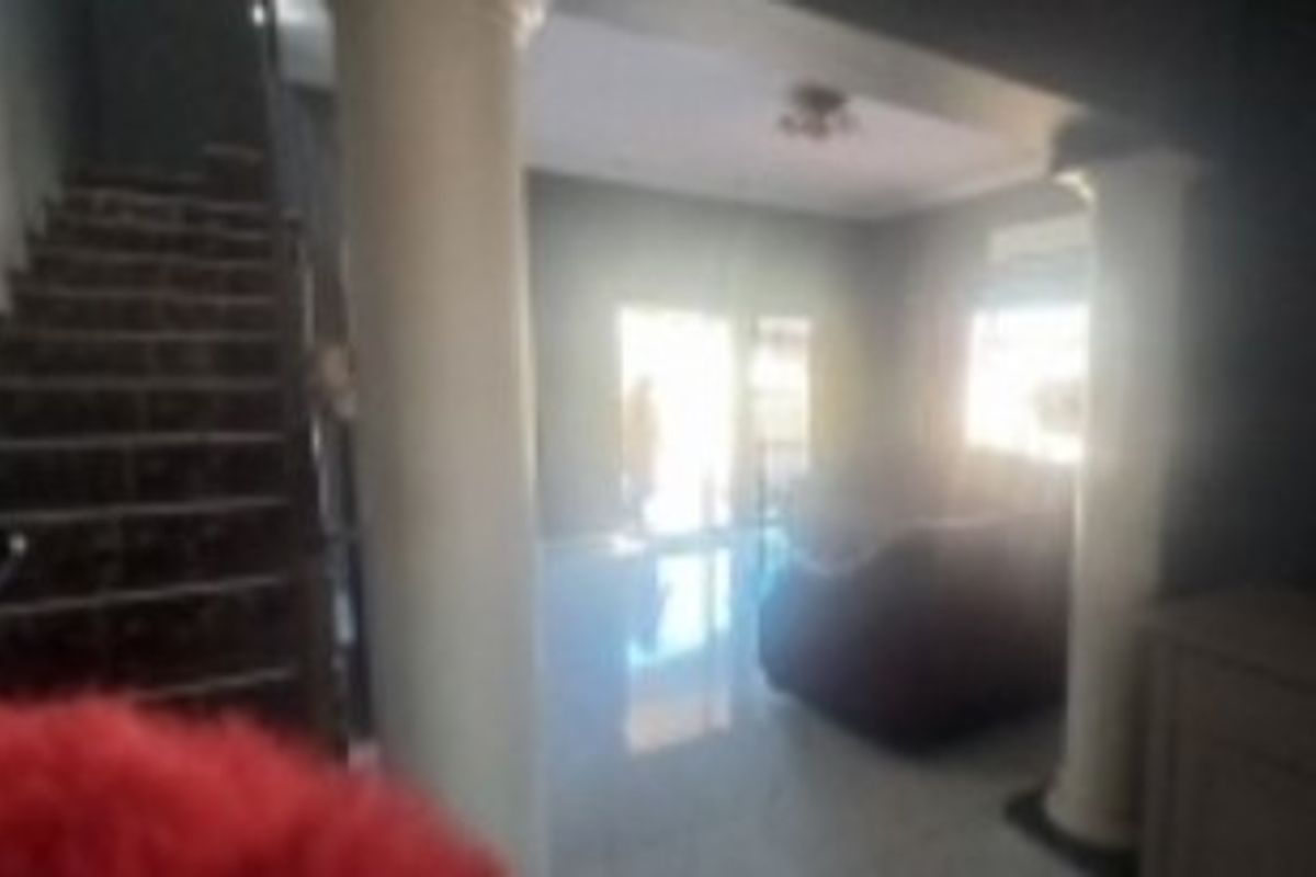 A living area featuring a staircase and decorative columns, with tiled flooring throughout.