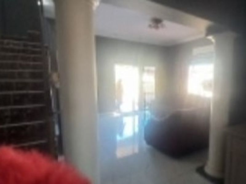 A living area featuring a staircase and decorative columns, with tiled flooring throughout.