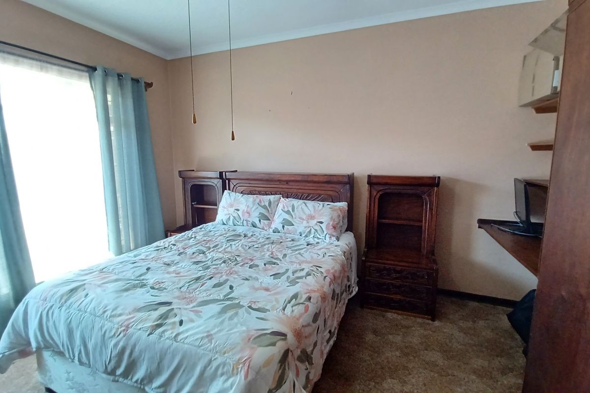 A functional bedroom featuring carpeted flooring, built-in shelving units, and a sliding door providing natural light access.