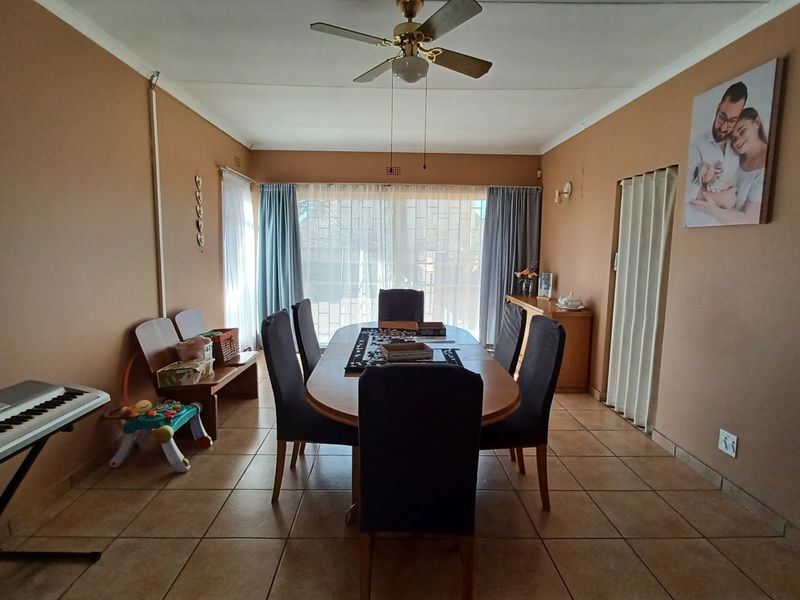 A functional dining room featuring tiled flooring, a ceiling fan, and a sliding door providing natural light.