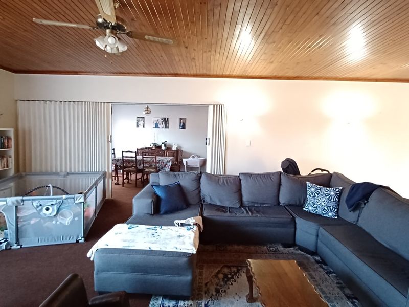 Spacious living area featuring a warm timber tongue and groove ceiling, ceiling fan, and a sliding partition leading to the adjacent dining space.