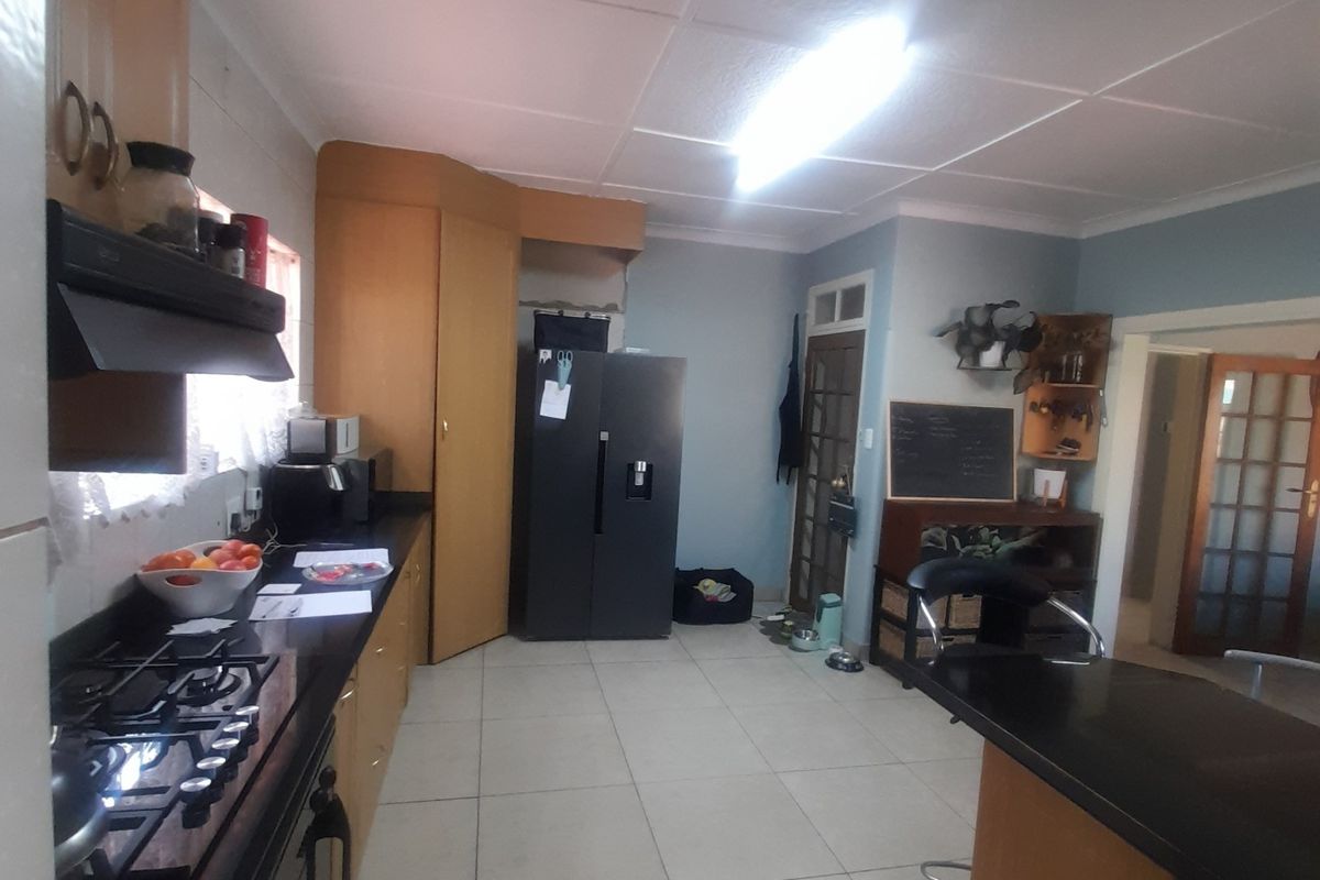 A functional kitchen featuring built-in cabinetry, a gas hob with extractor fan, tiled flooring, and a breakfast counter, offering potential for modern updates.