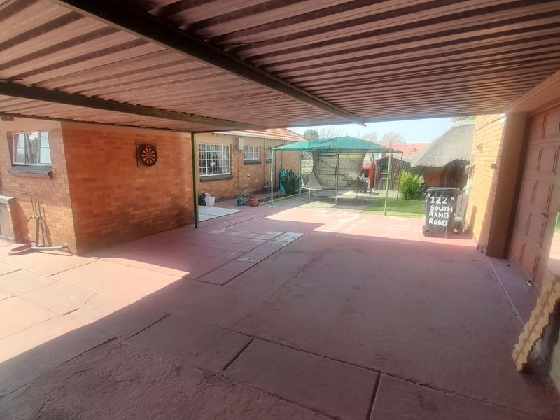 A covered outdoor patio area featuring brick walls, concrete flooring, and a corrugated metal roof, providing a functional space for outdoor activities.