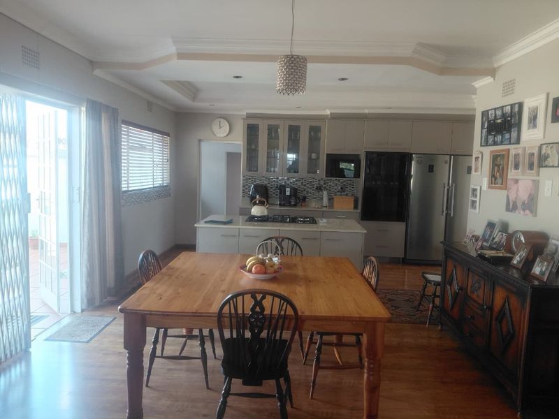 Spacious open-plan kitchen and dining area featuring modern cabinetry, a central island with a gas hob, and direct access to an outdoor patio.
