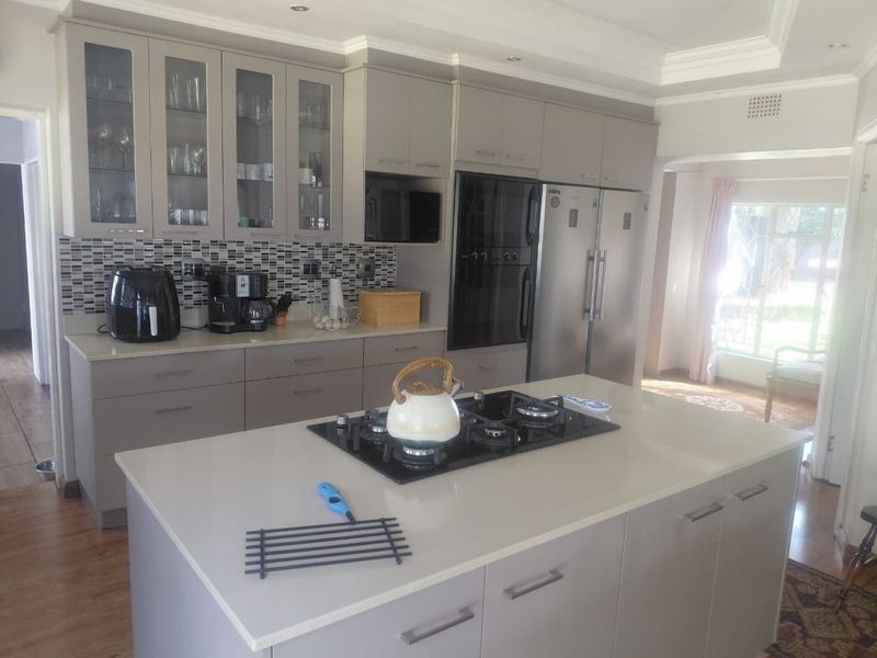 Modern kitchen featuring a central island with a gas cooktop, quartz countertops, sleek cabinetry, and a stylish mosaic tile backsplash.