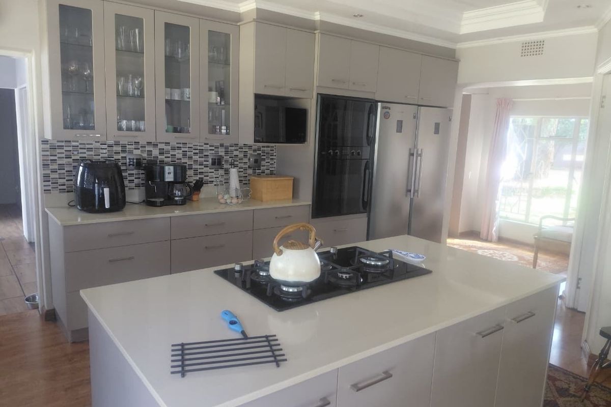Modern kitchen featuring a central island with a gas cooktop, quartz countertops, sleek cabinetry, and a stylish mosaic tile backsplash.