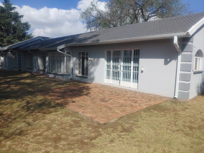 Rear view of the house featuring a brick paved patio area, tiled roof, and secure access points to the interior.