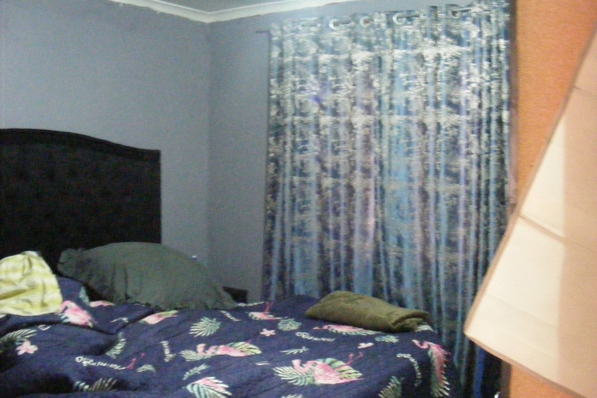 A bedroom featuring grey walls and a curtained window, providing a functional sleeping space.