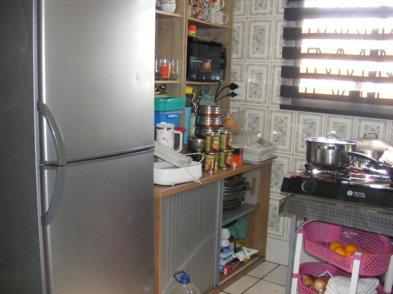 A compact kitchen area featuring built-in cabinetry, tiled wall finishes, and tiled flooring, offering a functional space with potential for modernization.
