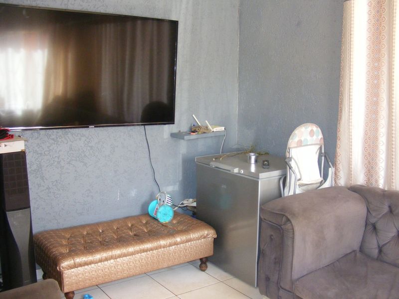A living room area featuring tiled flooring and textured grey walls, providing a functional space for relaxation.