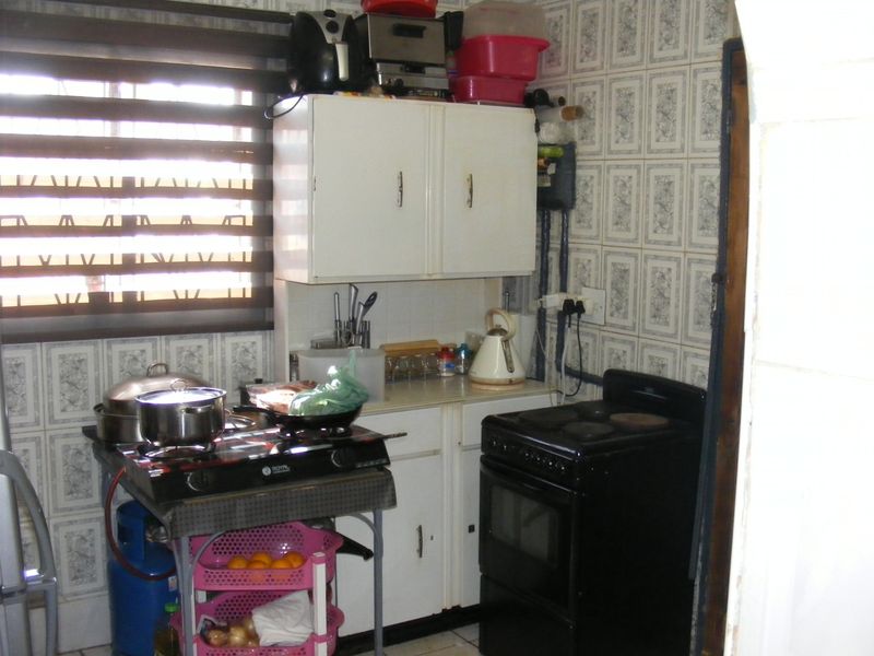 A compact kitchen area featuring built-in cabinetry and tiled wall finishes, requiring modernization to improve functionality and aesthetic appeal.