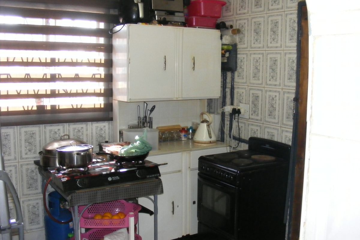A compact kitchen area featuring built-in cabinetry and tiled wall finishes, requiring modernization to improve functionality and aesthetic appeal.