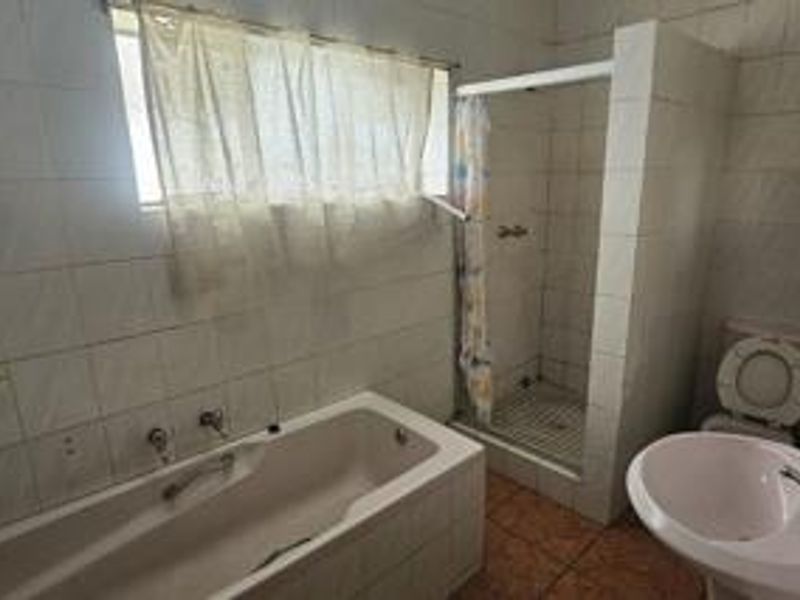 A dated bathroom featuring a built-in bathtub, separate shower enclosure, pedestal sink, and toilet with full-height wall tiling.