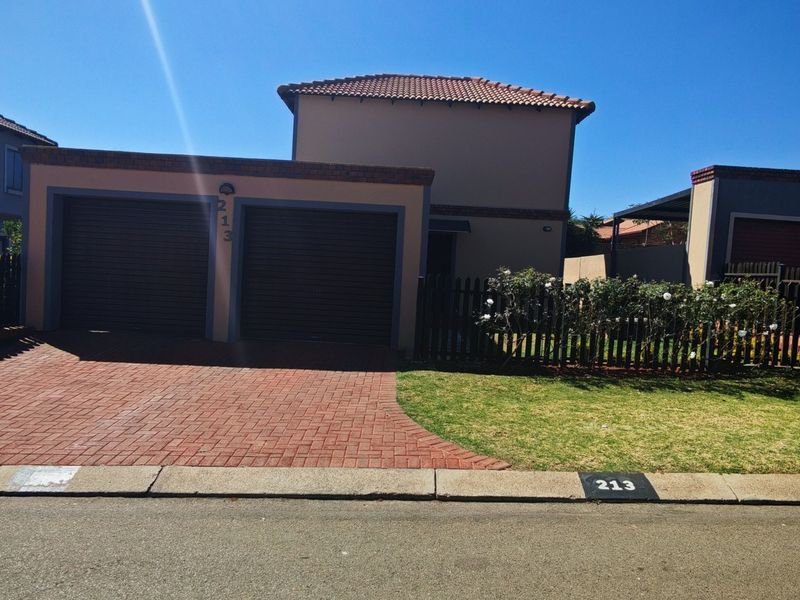 Front elevation of a residential property featuring a double garage, brick paved driveway, and a well-maintained front lawn.