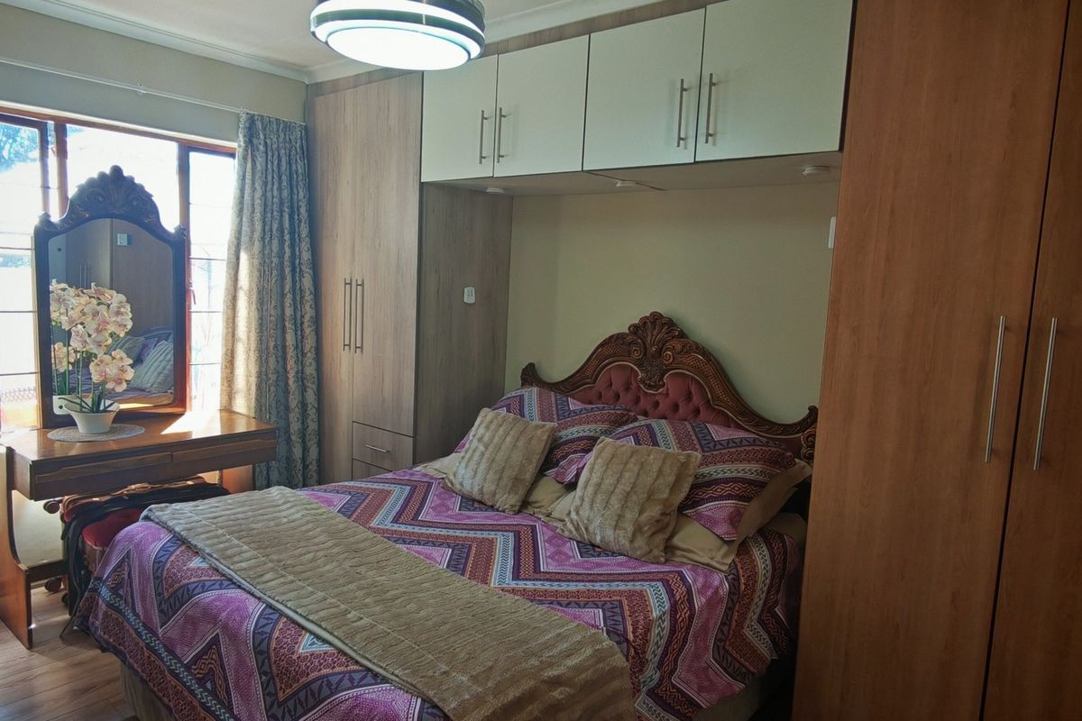 A bedroom featuring built-in wooden cupboards and overhead storage cabinets, providing ample storage space with laminate flooring throughout.