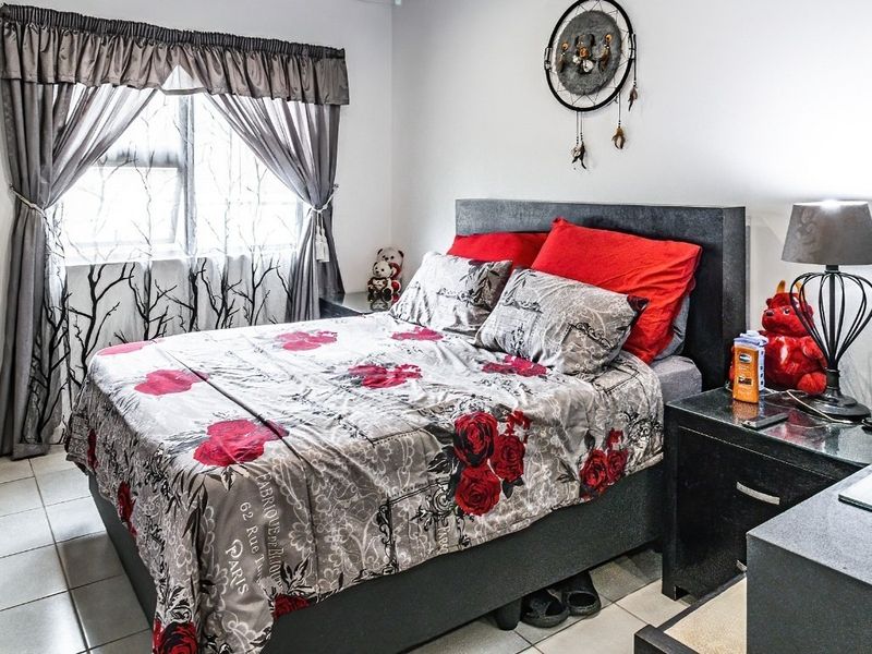 A functional bedroom featuring tiled flooring, a built-in wardrobe, and a window with curtain treatments, offering a clean and practical living space.