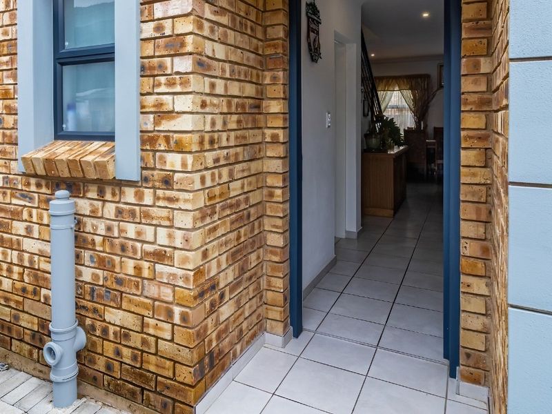 A welcoming townhouse entrance featuring a classic face brick facade, tiled flooring, and a clear view into the interior living space.