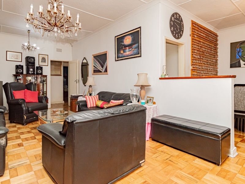 Open plan living and dining area featuring classic parquet flooring, a partition wall, and decorative ceiling fixtures.