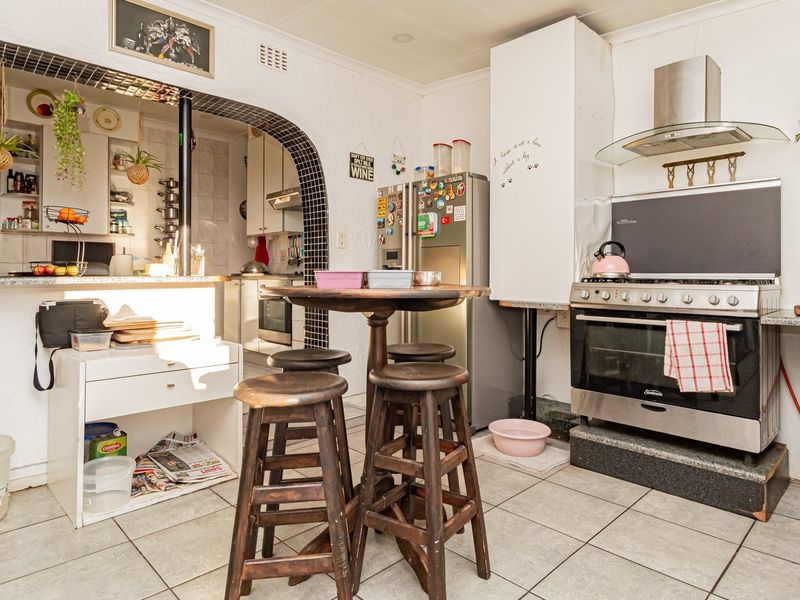 A functional kitchen featuring tiled flooring, a gas stove with extractor fan, and an arched opening leading to an adjacent prep area.
