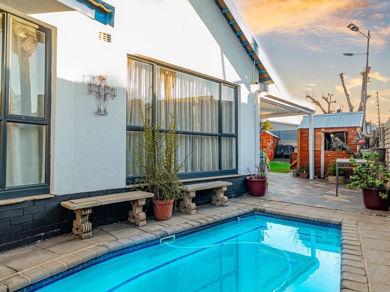 Outdoor pool area featuring a paved surround, integrated covered patio space, and secure perimeter electric fencing.