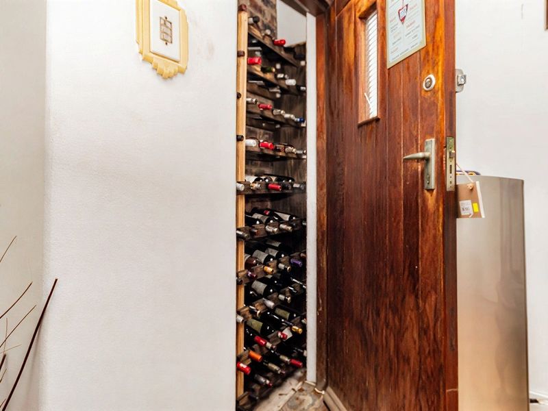 A dedicated built-in wine storage cellar featuring custom timber racking, accessed via a solid timber door.