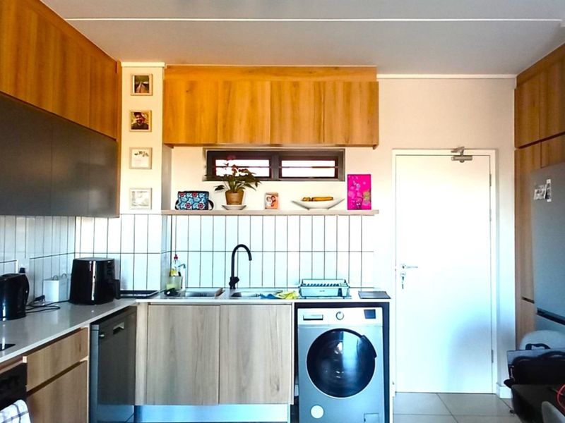 A modern, well-maintained kitchen featuring light wood cabinetry, a tiled backsplash, integrated appliances, and a sleek faucet, offering a clean and functional workspace.