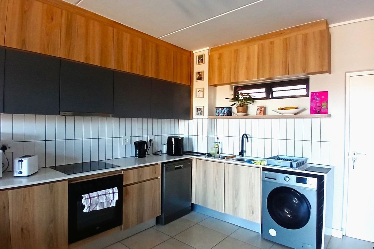 Modern kitchen featuring two-tone wood and dark grey cabinetry, tiled backsplash, built-in oven, electric hob, and integrated dishwasher.