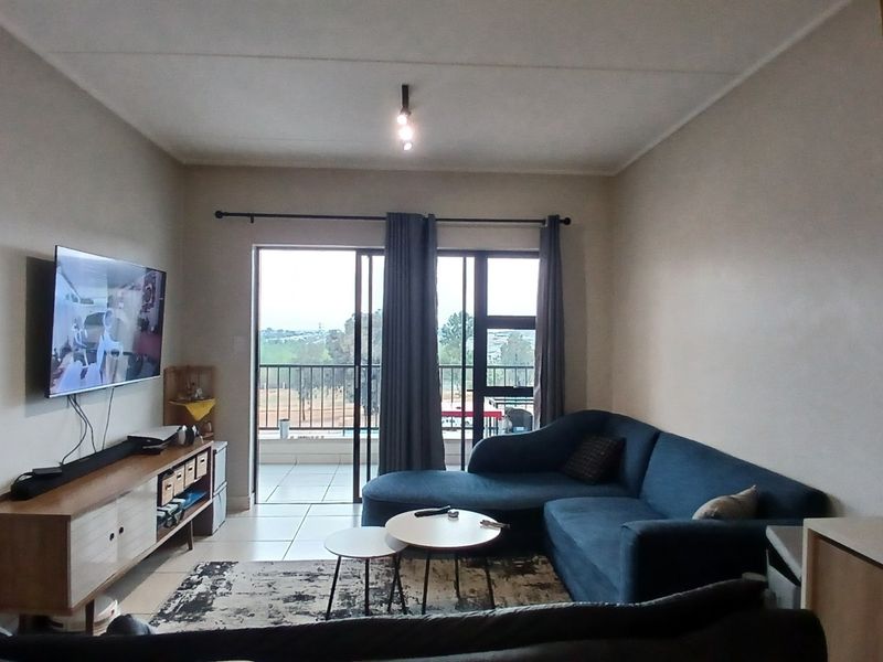 Open plan living area featuring tiled floors and a sliding glass door leading to a balcony, providing natural light and outdoor access.